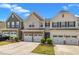 Street view of townhomes featuring two-car garages and well-maintained landscaping under a vibrant blue sky at 4137 Lofty Ridge Pl, Morrisville, NC 27560