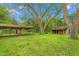 Wide backyard view featuring a shed, covered area, grass and several trees at 429 N Asheboro St, Liberty, NC 27298