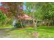 Inviting two-story home with a metal roof, front porch, and mature trees in a lush green yard at 429 N Asheboro St, Liberty, NC 27298