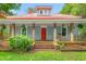 Inviting front porch with wood columns, railings, hanging plants, and a bright red door adds a touch of character at 429 N Asheboro St, Liberty, NC 27298