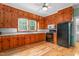 Traditional kitchen with knotty pine cabinets, black appliances, and hardwood floors at 429 N Asheboro St, Liberty, NC 27298