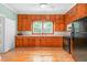 Traditional kitchen with knotty pine cabinets, black appliances, and wood floors at 429 N Asheboro St, Liberty, NC 27298