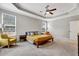 Bright main bedroom featuring large windows, neutral tones, and tray ceilings with a ceiling fan at 4405 Aubaun Way, Knightdale, NC 27545