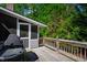 Wooden back deck surrounded by trees and greenery, featuring a grill and a door leading to the house at 4900 Old Millcrest Ct, Raleigh, NC 27609