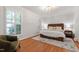Bedroom with hardwood floors, a king bed, bedside tables, and an accent chair at 4900 Old Millcrest Ct, Raleigh, NC 27609