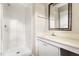 Bright bathroom with a walk-in shower featuring white tiles and a vanity area with a framed mirror at 5802 Newhall Rd, Durham, NC 27713