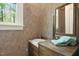 This bathroom features a patterned wall, a single sink, a window, and a wooden cabinet with a large mirror at 6000 Canadero Dr, Raleigh, NC 27612
