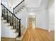 Bright foyer with hardwood floors, a staircase with black railings, and a view into the living areas at 6000 Canadero Dr, Raleigh, NC 27612