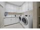 Bright laundry room featuring front loading washer and dryer, built in cabinets, sink, and white walls at 6000 Canadero Dr, Raleigh, NC 27612