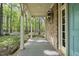 Inviting covered porch with brick columns, a stylish lantern, and serene views of the surrounding trees at 6000 Canadero Dr, Raleigh, NC 27612