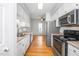 A bright kitchen with white cabinets, stainless steel appliances, and hardwood floors at 6000 Tenter Banks Sq, Raleigh, NC 27609