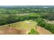 Aerial view of a beautiful home surrounded by trees, fields, and a lake at 675 Anderson Creek Rd, Henderson, NC 27537