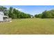 Spacious backyard featuring a well-kept lawn, mature trees, and a glimpse of the charming farmhouse at 675 Anderson Creek Rd, Henderson, NC 27537