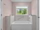 Tranquil bathroom featuring a white tub, a window, and tile surround at 675 Anderson Creek Rd, Henderson, NC 27537
