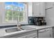 Bright kitchen featuring blue backsplash, stainless sink, white cabinets and quartz counters at 675 Anderson Creek Rd, Henderson, NC 27537