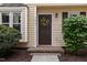 Close-up of front door featuring a colorful wreath and neat landscaping at 7015 Staghorn Ln, Raleigh, NC 27615