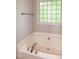 Bathroom features a glass block window, shower, and soaking tub at 71 Hunters Way, Angier, NC 27501