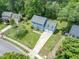 Aerial view of a blue two story home with a long driveway and a two car garage, surrounded by green lawns and trees at 7209 Halstead Ln, Raleigh, NC 27613