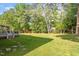 Spacious backyard featuring a large lawn, mature trees and shrubs, and a deck with screened in porch at 7209 Halstead Ln, Raleigh, NC 27613