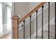 Close-up of a staircase featuring a wooden handrail and black iron balusters with white trim and carpeted steps at 7209 Halstead Ln, Raleigh, NC 27613