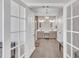 View of the primary bathroom through french doors, showcasing double vanity sinks, tile floors, and elegant lighting at 725 S State St, Raleigh, NC 27601