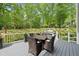Large deck with a dining table, chairs, and outdoor kitchen overlooking a wooded backyard at 7517 Summer Pines Way, Wake Forest, NC 27587
