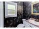Stylish half-bathroom with unique wallpaper, modern fixtures, and a decorative mirror at 8124 Greywinds Dr, Raleigh, NC 27615