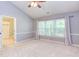 Cozy bedroom featuring carpet floors, large windows, neutral wall colors, a ceiling fan, and an ensuite bathroom at 8124 Greywinds Dr, Raleigh, NC 27615