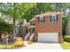 Two-story brick home with black shutters, an attached garage, and mature trees at 8124 Greywinds Dr, Raleigh, NC 27615