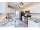 Well-lit kitchen boasts granite counters, white cabinetry, stainless-steel appliances, and tiled floors at 8124 Greywinds Dr, Raleigh, NC 27615