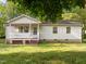 Quaint one-story home with white siding, front porch, and mature trees at 84 Honeysuckle Dr, Pittsboro, NC 27312