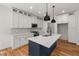 Stylish kitchen showcasing white cabinets, a navy island, stainless appliances, and modern fixtures at 1005 Forrestal Pl, Durham, NC 27707