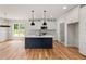 Modern kitchen with white cabinets, a blue island, pendant lighting, and hardwood floors at 1005 Forrestal Pl, Durham, NC 27707