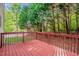 View of the red painted wooden deck and lush green trees in the backyard at 101 Hay Sedge Ct, Durham, NC 27705