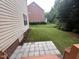 Inviting backyard featuring a small paver patio, lush green grass, and lovely landscaping at 102 Revere Forest Ct, Cary, NC 27519