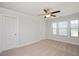 Carpeted bedroom with a ceiling fan and two windows overlooking an outdoor view with walk-in closet at 103 Ballyliffen Ln, Cary, NC 27519