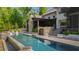 The backyard has a sleek pool with a stone wall, lounge chairs, and verdant trees at 103 Patriot Way, Apex, NC 27523