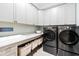 Modern laundry room featuring sleek appliances and ample storage with gray cabinets and granite countertops at 103 Patriot Way, Apex, NC 27523