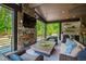 Luxurious outdoor living space with stone fireplace, comfortable seating, and views of the natural landscape at 103 Patriot Way, Apex, NC 27523