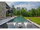 Stunning backyard featuring a modern pool with white lounge chairs, lush greenery and privacy trees around property at 103 Patriot Way, Apex, NC 27523