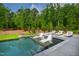 Relaxing pool area featuring in-pool loungers and a beautifully landscaped backyard with green trees and grass at 103 Patriot Way, Apex, NC 27523