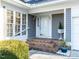The covered front porch features brick steps, gray siding, and a glass front door flanked by a window at 11 Whitburn Pl, Durham, NC 27705