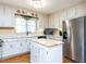 Kitchen features white cabinets, an island, stainless steel refrigerator, hardwood floors, and plenty of storage at 11 Whitburn Pl, Durham, NC 27705