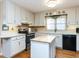 Kitchen features white cabinets, an island, black appliances, hardwood floors, and plenty of storage at 11 Whitburn Pl, Durham, NC 27705