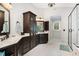Bathroom featuring dual sinks, dark cabinets, and a glass-enclosed shower for a luxurious feel at 112 Aspenridge Dr, Holly Springs, NC 27540