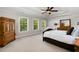 Bright bedroom features a tray ceiling, three windows, a ceiling fan and wood furniture at 112 Aspenridge Dr, Holly Springs, NC 27540