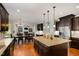Open-concept kitchen features dark cabinets, stainless appliances, large granite island and adjacent dining area at 112 Aspenridge Dr, Holly Springs, NC 27540