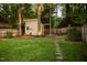 Large grassy backyard featuring a storage shed, a swing and established trees at 112 E Edgewood Dr, Durham, NC 27704