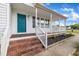 Inviting covered front porch with brick steps, white railings, and a teal door at 112 Edmondson Dr, Willow Springs, NC 27592