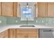 Stylish kitchen showcasing a stainless steel dishwasher, wood cabinets and contrasting backsplash for a modern touch at 112 Edmondson Dr, Willow Springs, NC 27592